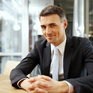 happy-businessman-sitting-at-the-table-in-office-CXCLT9V